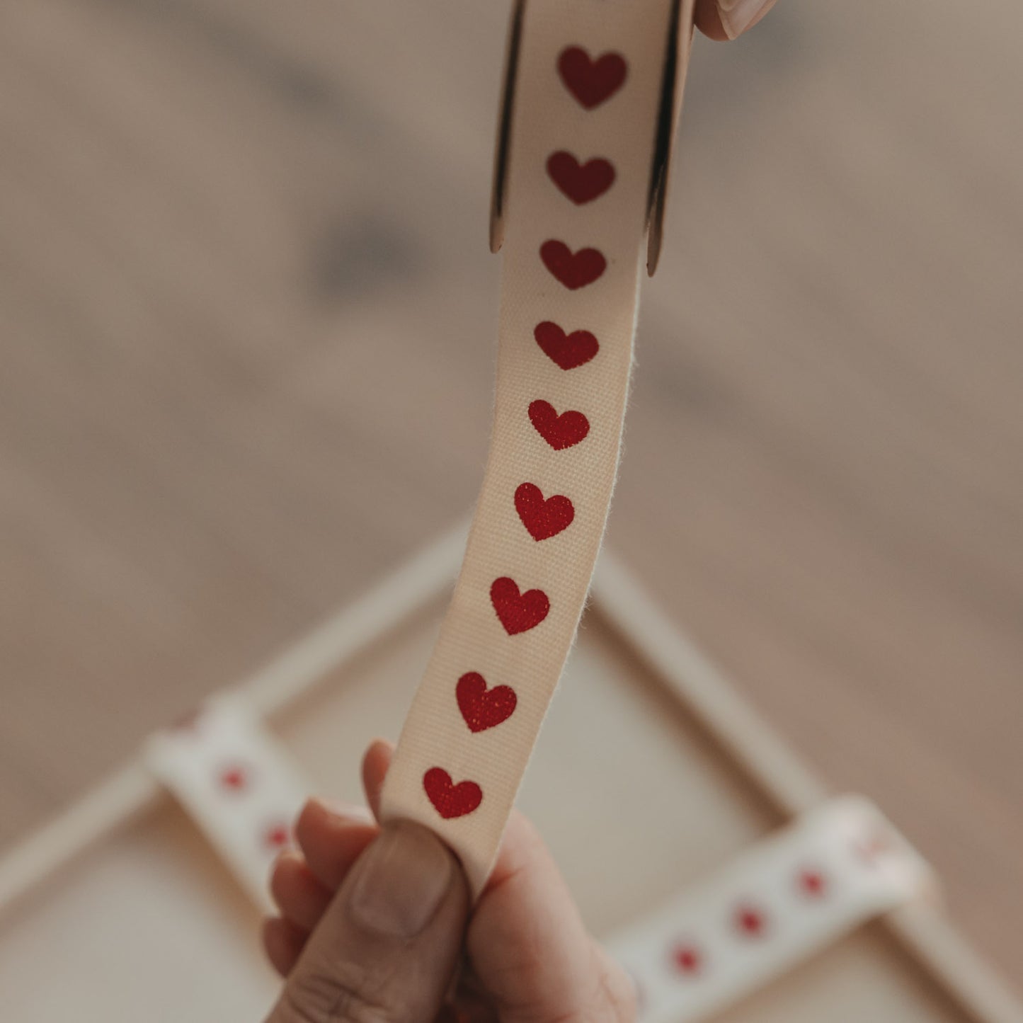 Detailansicht von beigem Geschenkband mit roten Herzen auf einer Rolle