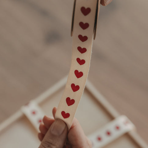 Detailansicht von beigem Geschenkband mit roten Herzen auf einer Rolle