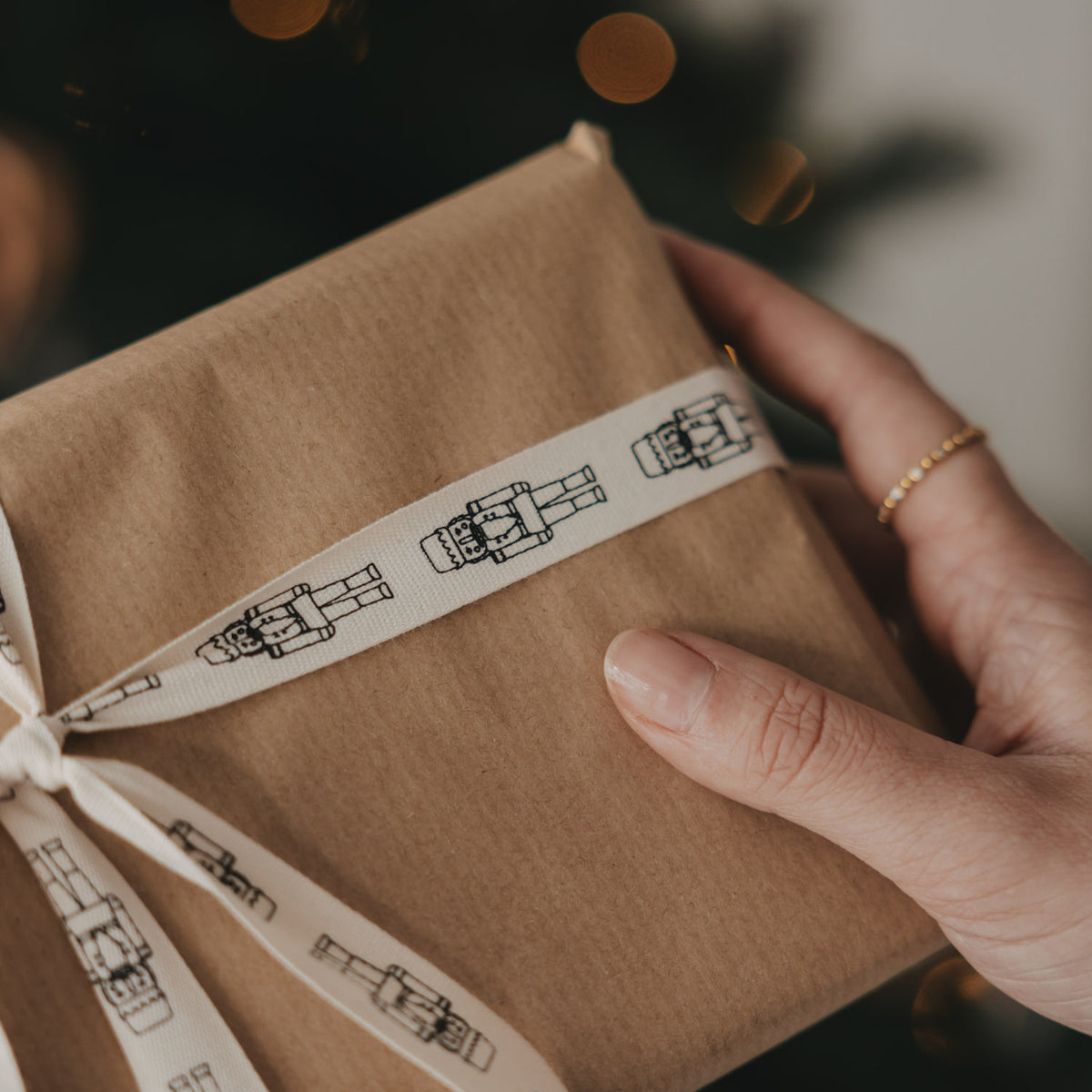 Weihnachtsgeschenk in Kraftpapier mit beigem Geschenkband und Nussknacker-Motiv