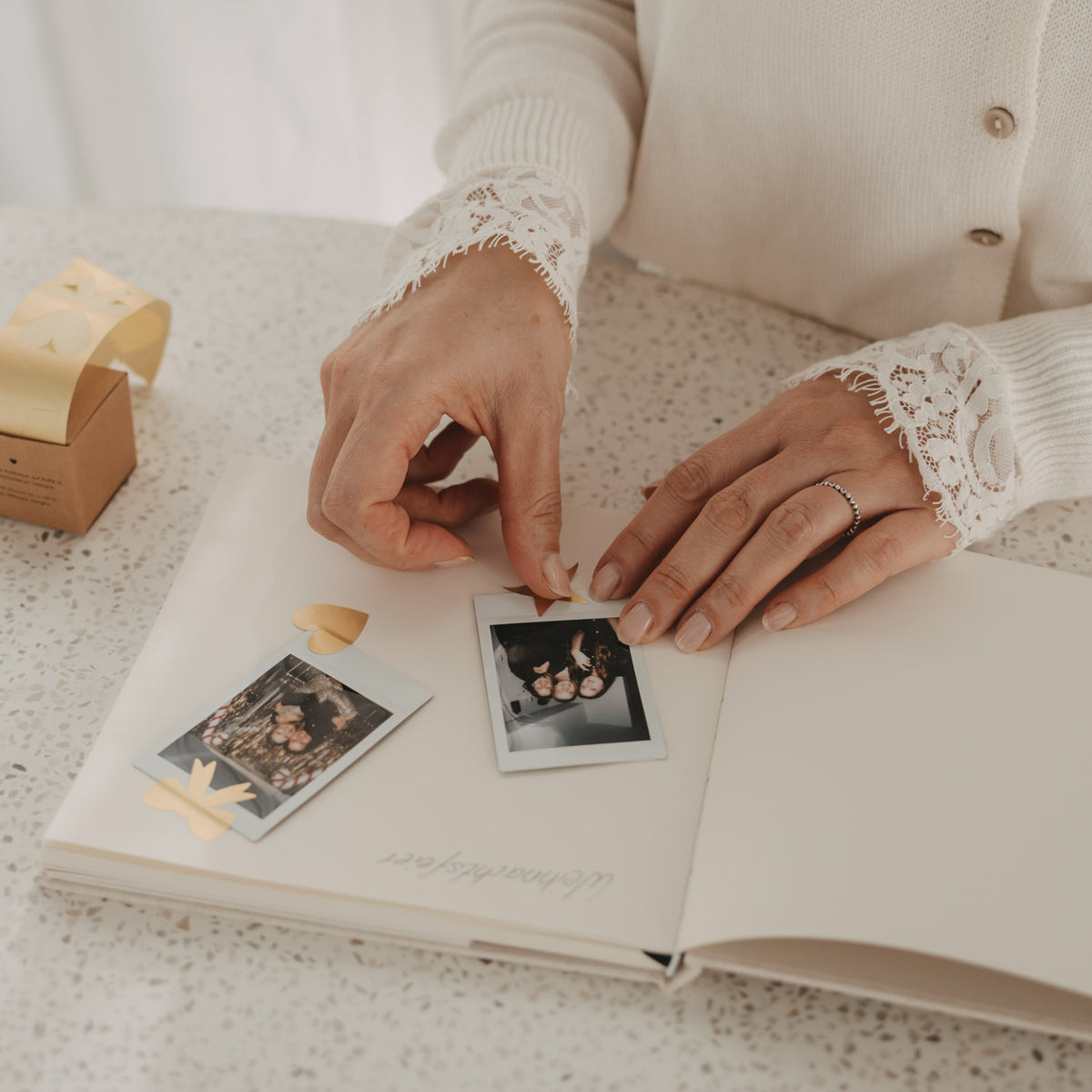 Offenes Gästebuch mit Blankoseiten beim Einkleben von Fotos und goldenen Stickern