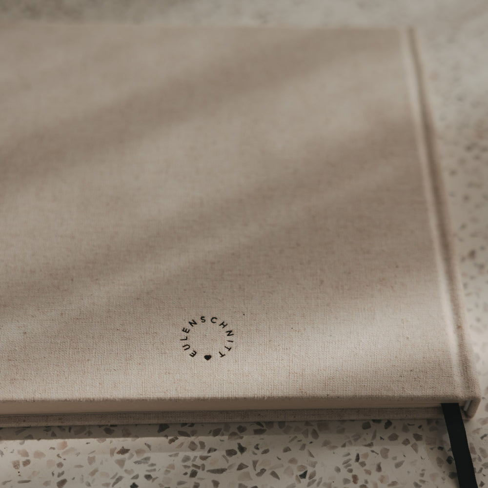 Rückseite des beigen Buchs mit Eulenschnitt Logo, Leineneinband und schwarzem Leseband