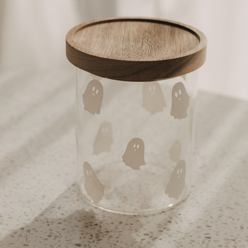 Vorratsglas mit weißen Geistern und rundem Holzdeckel als dekorative Aufbewahrung