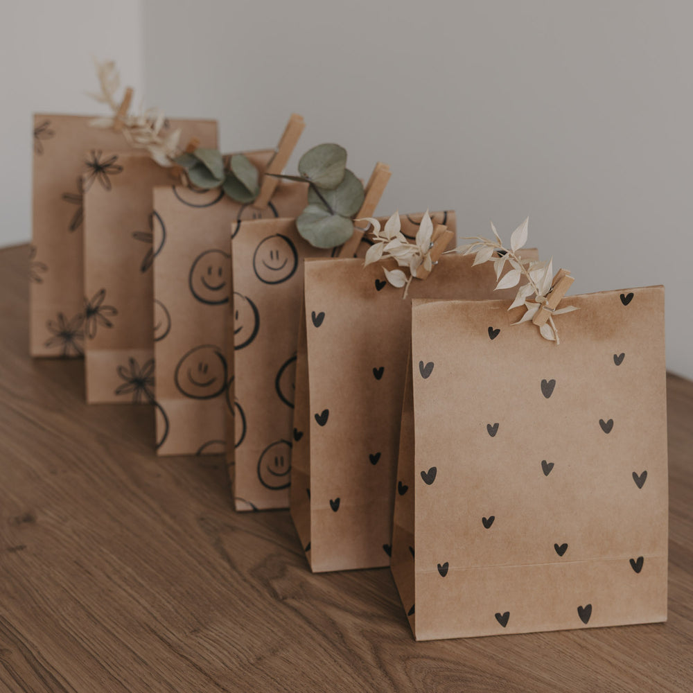 Geschenkbeutel aus Kraftpapier mit schwarzem Herzmuster, dekorativ gefaltet und mit Trockenblumen verziert