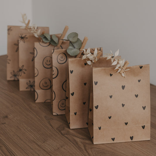 Geschenkbeutel aus Kraftpapier mit schwarzem Herzmuster, dekorativ gefaltet und mit Trockenblumen verziert