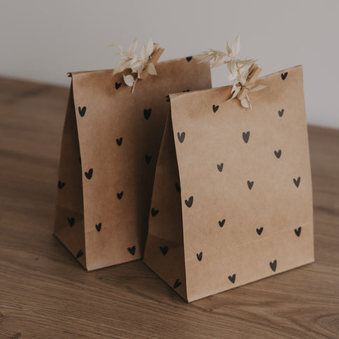 Zwei braune Geschenktüten aus Papier mit kleinen schwarzen Herzen, liebevoll dekoriert mit Holzklammern