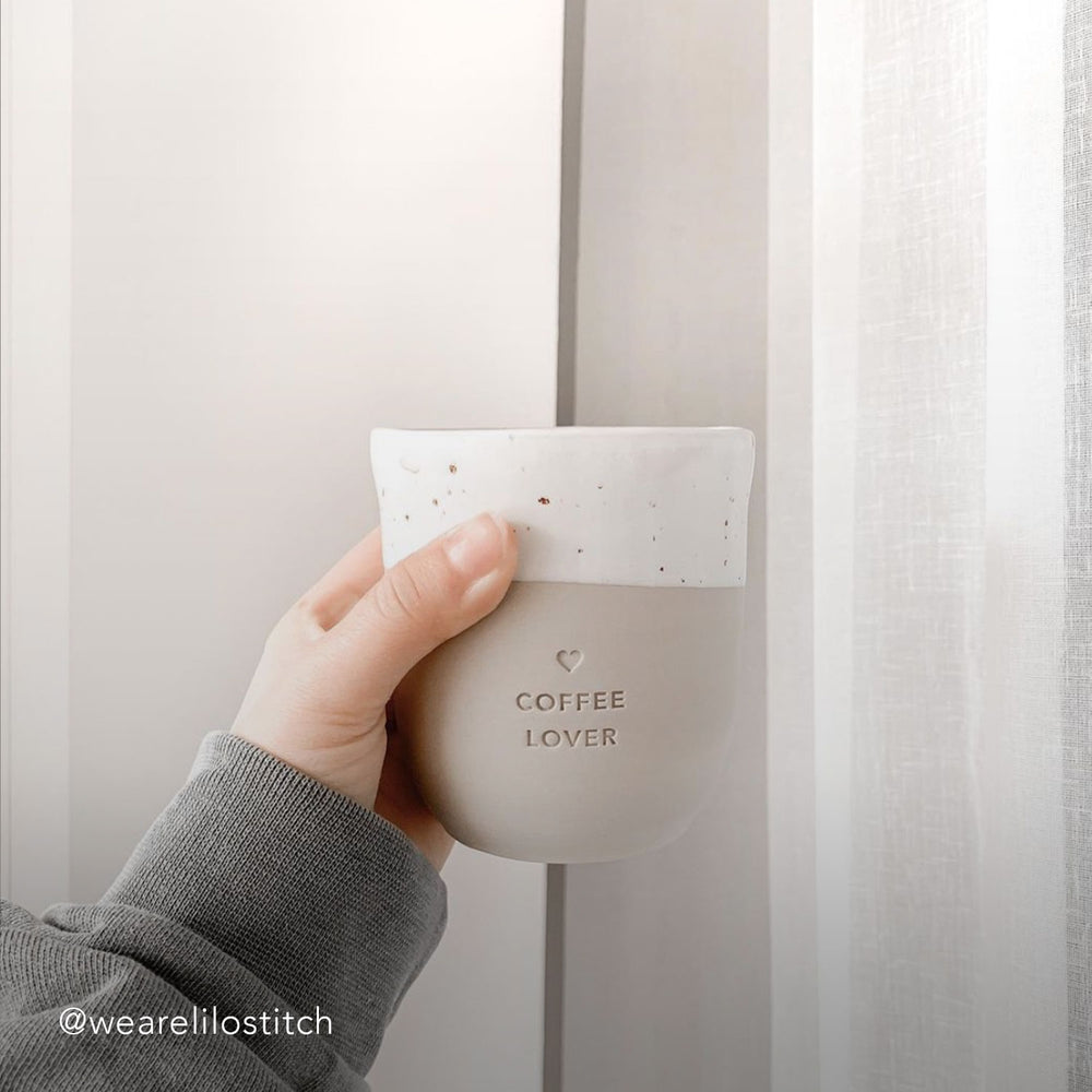 Eine Frauenhand hält einen Becher mit der Prägung "Coffee Lover".