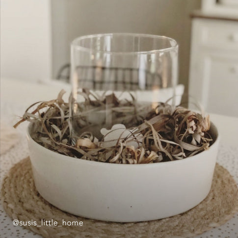 Keramikschale mit hellem Rand, gefüllt mit Dekozweigen und einem Glaszylinder in der Mitte. Die Szene ist in einem gemütlichen Zuhause aufgenommen. Unten links steht der Instagram-Name: @susi_little_home.