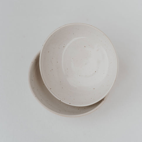 Zwei übereinandergelegte Schalen aus gesprenkelter Keramik auf weißem Untergrund.